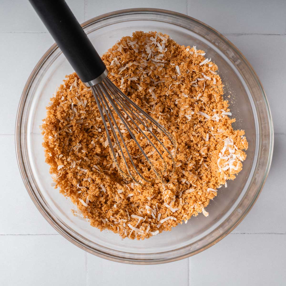 Whisking graham crackers with spices and shredded coconut.