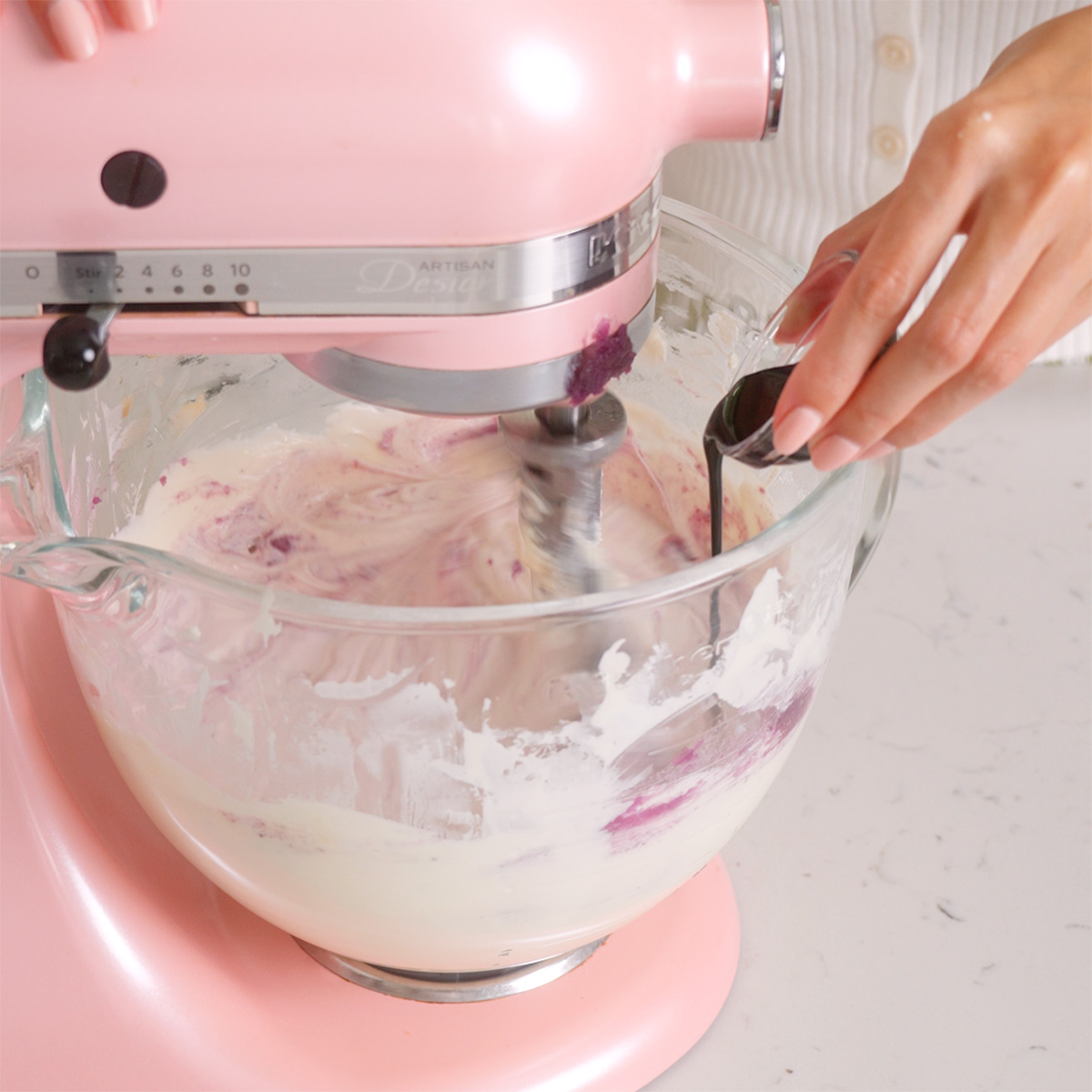 Adding ube extract into a stand mixer creaming cream cheese.