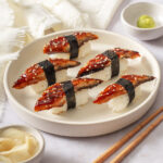 A plate of several unagi sushi pieces.