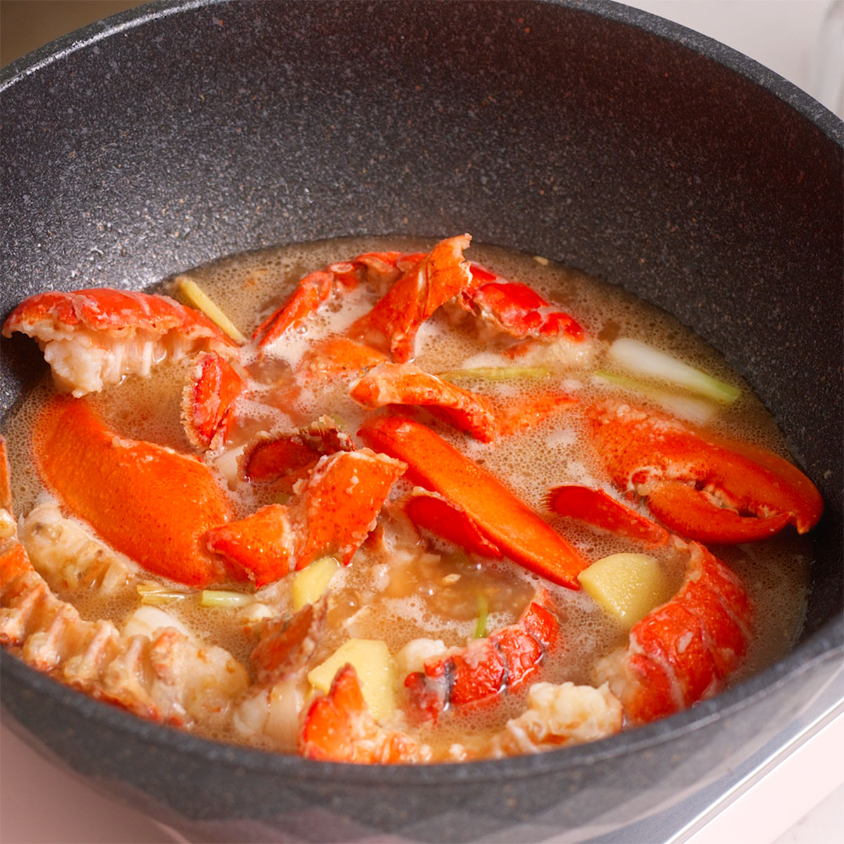 Fried lobster and aromatics cooking in a sauce.