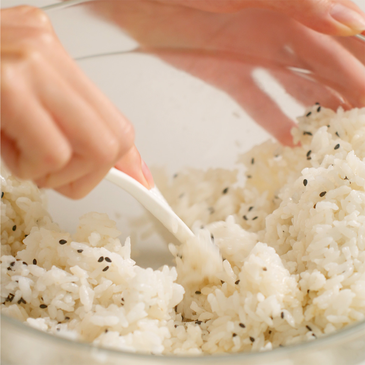 Mixing sushi rice with seasoning and black sesame seeds.