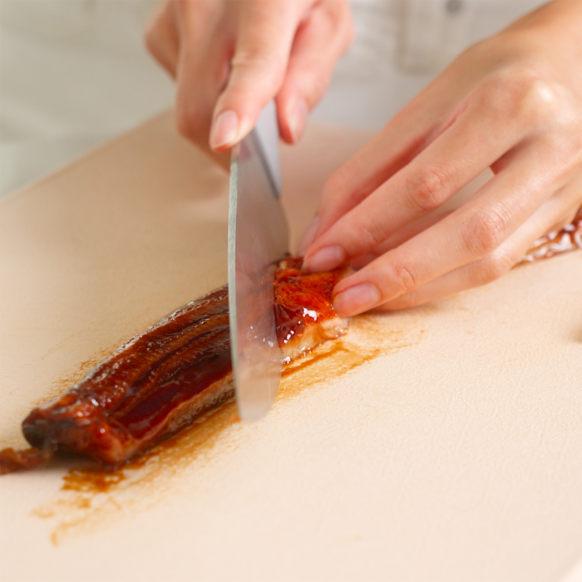 Slicing grilled unagi into pieces for sushi.