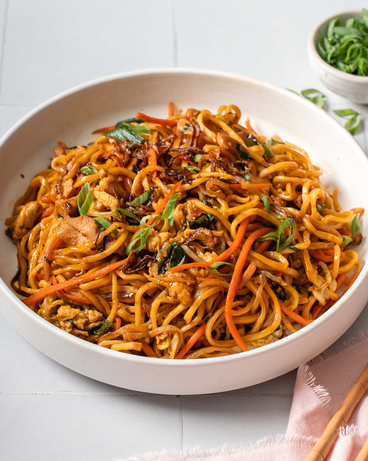 A plate of bami goreng on a tiled surface.