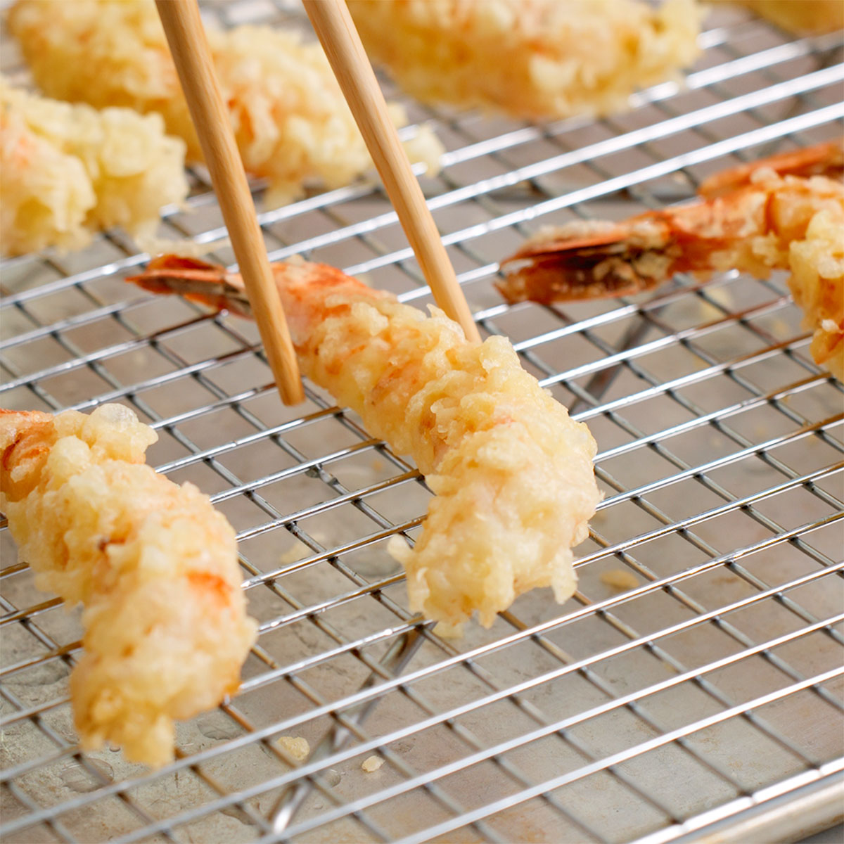 Setting a fried ebi tempura on a drying rack.