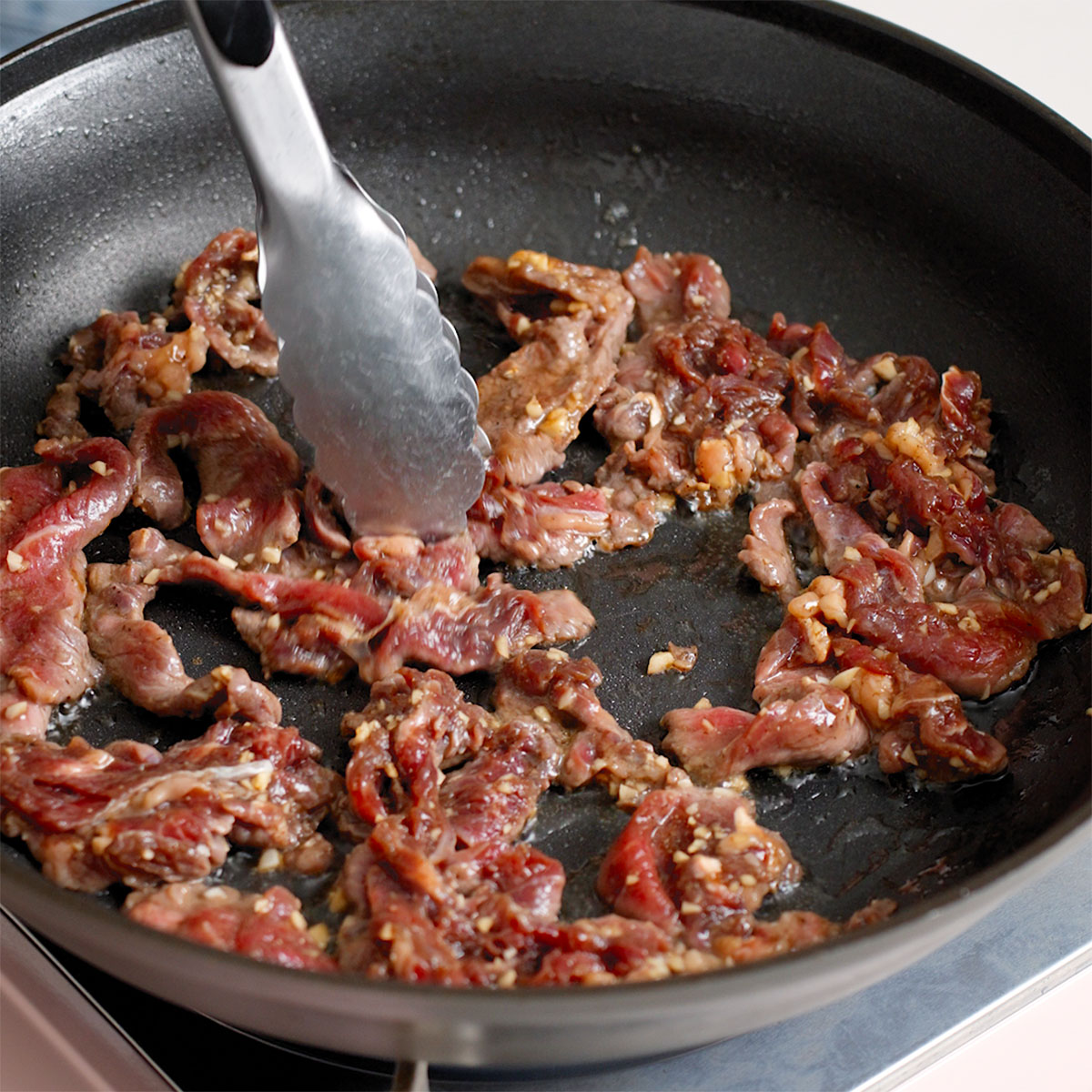 Cooking sliced beef in a large skillet.