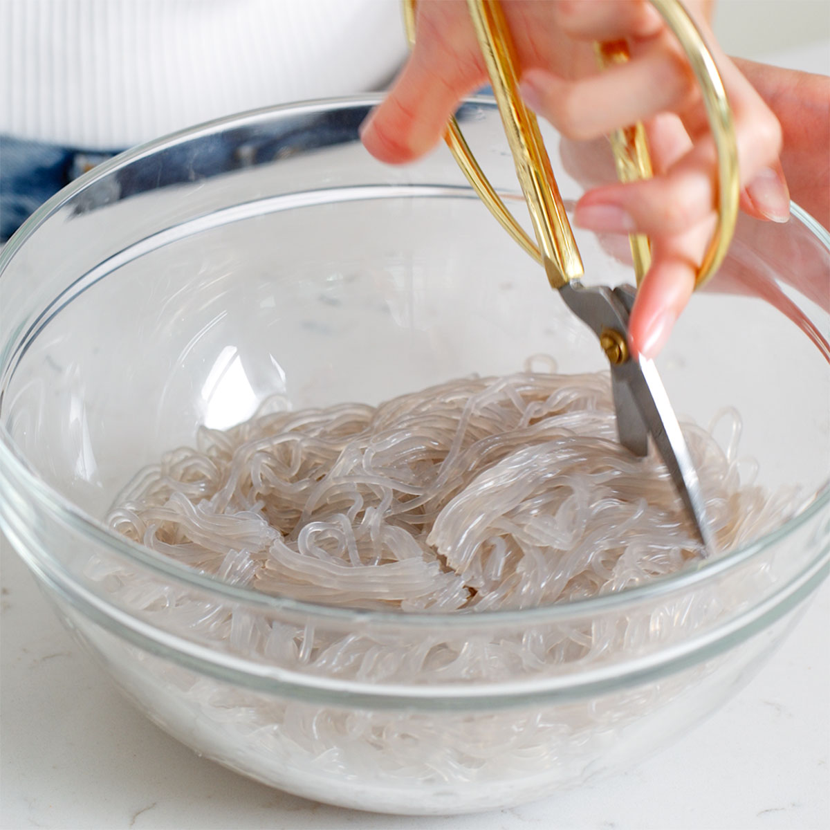 Cutting freshly cooked glass noodles with a pair of scizzors.