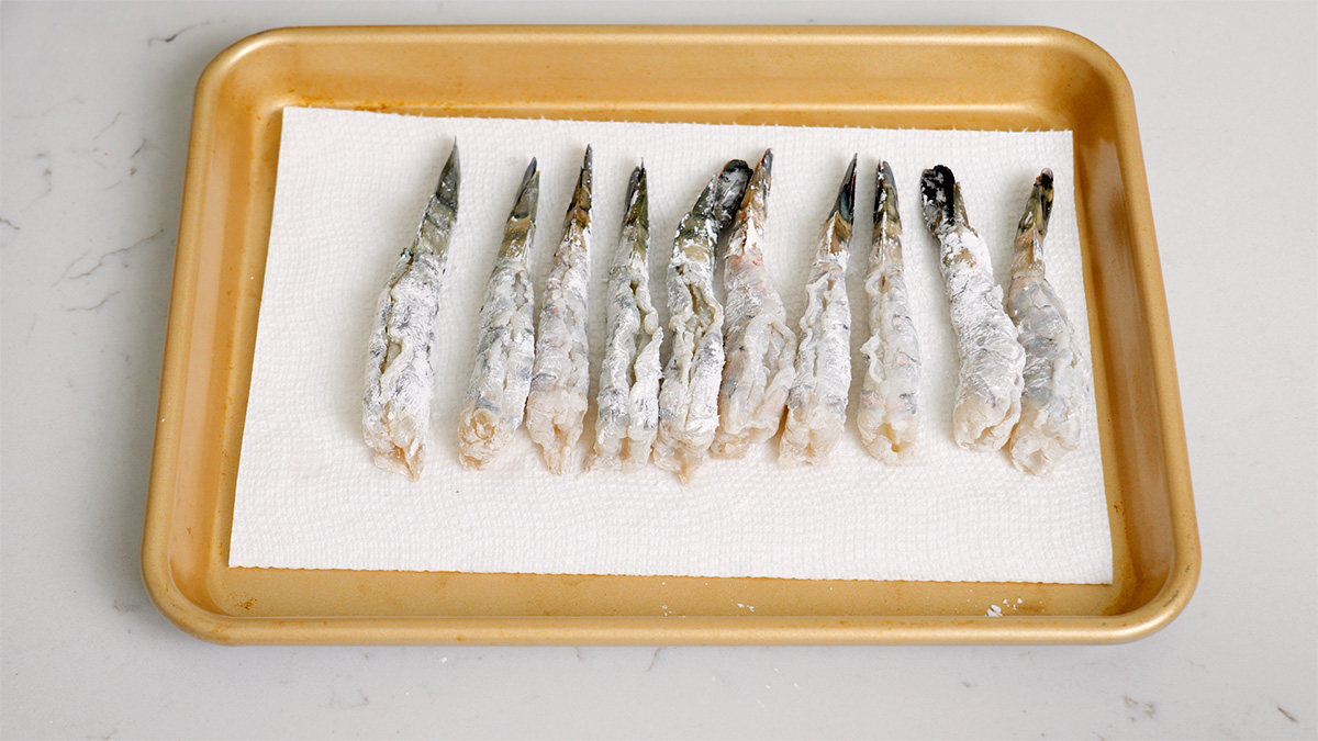 Shrimp dredged in cornstarch to prepare for tempura.