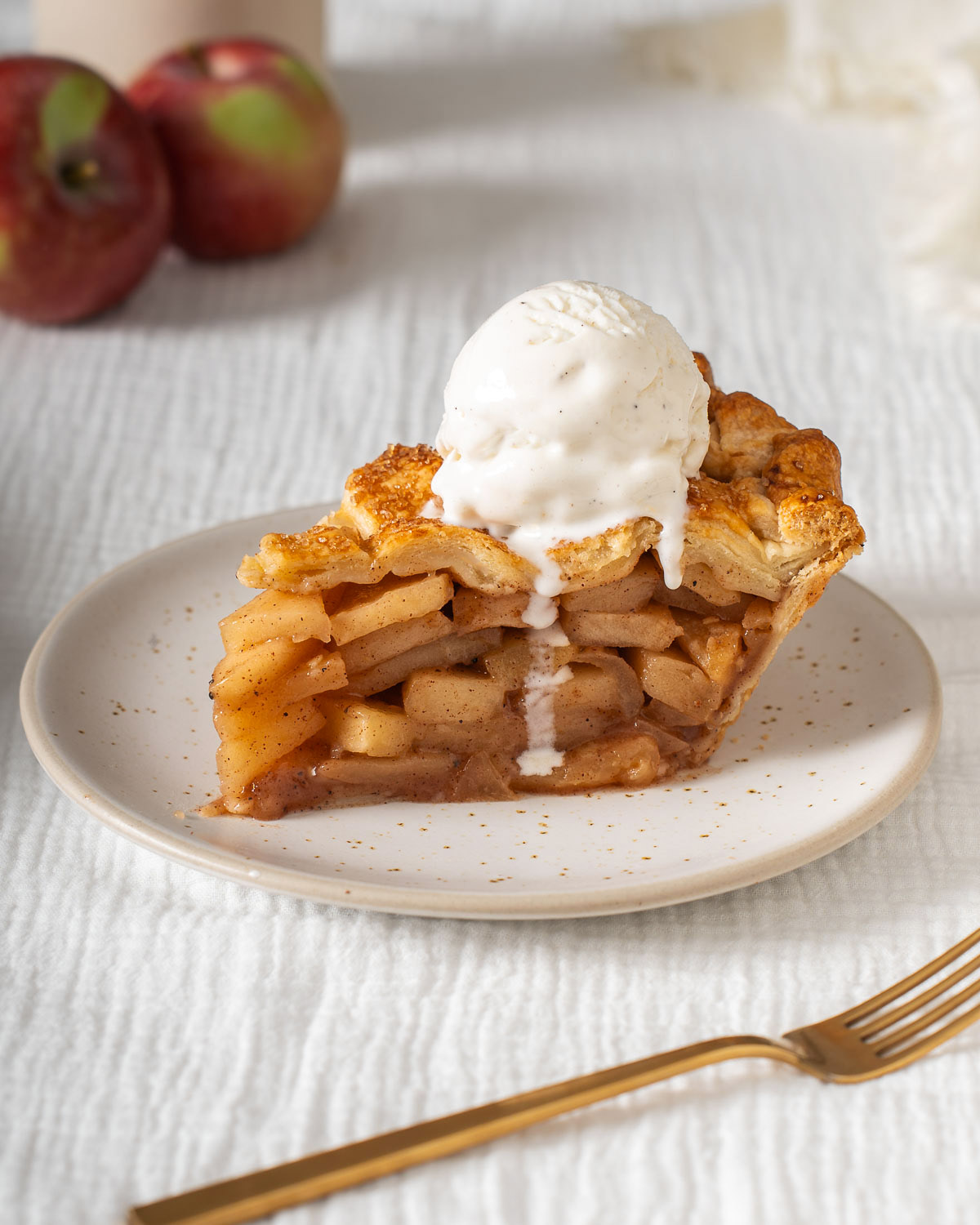 A slice of homemade apple pie with a scoop of vanilla ice cream on top.