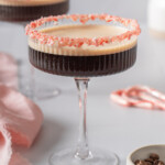 Two coup glasses filled. with peppermint espresso martini with peppermint candy rims.