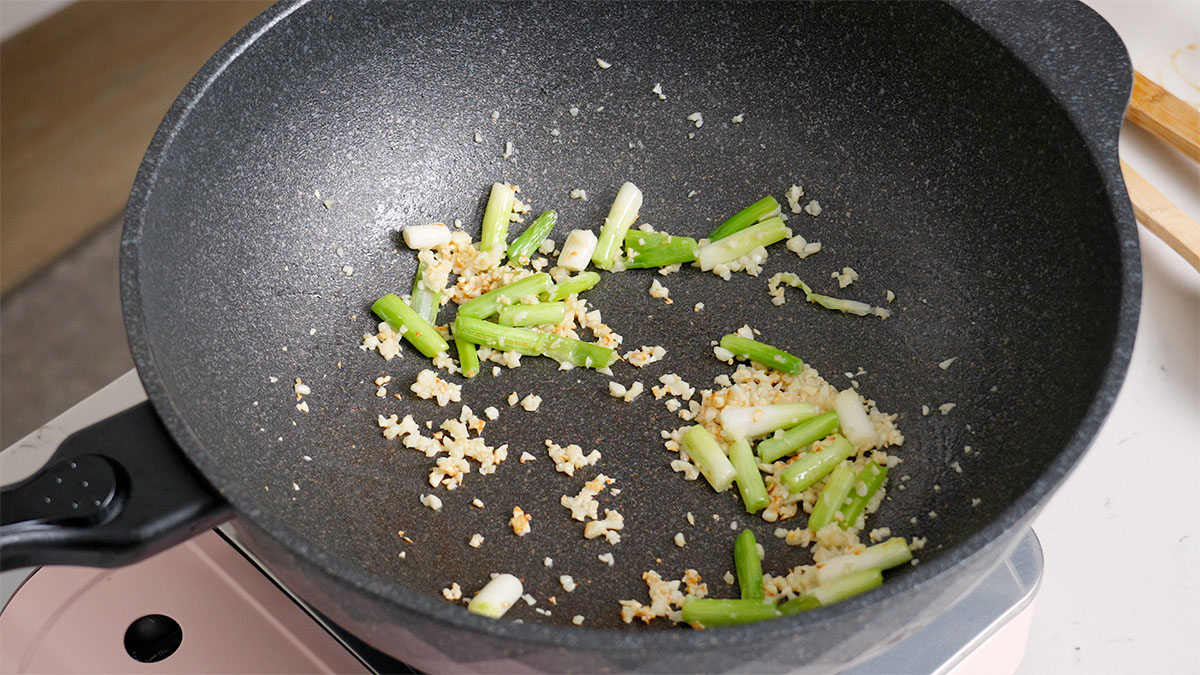 Sauteeing aromatics inside a large wok.