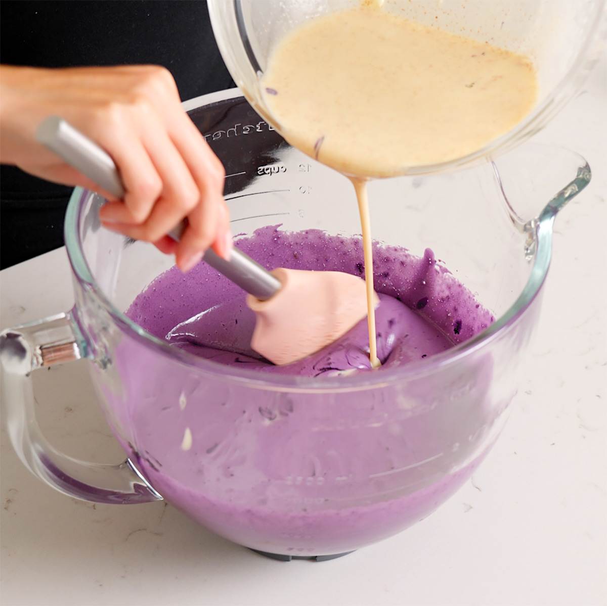 Pouring melted chocolate into a whipped ube mixture.