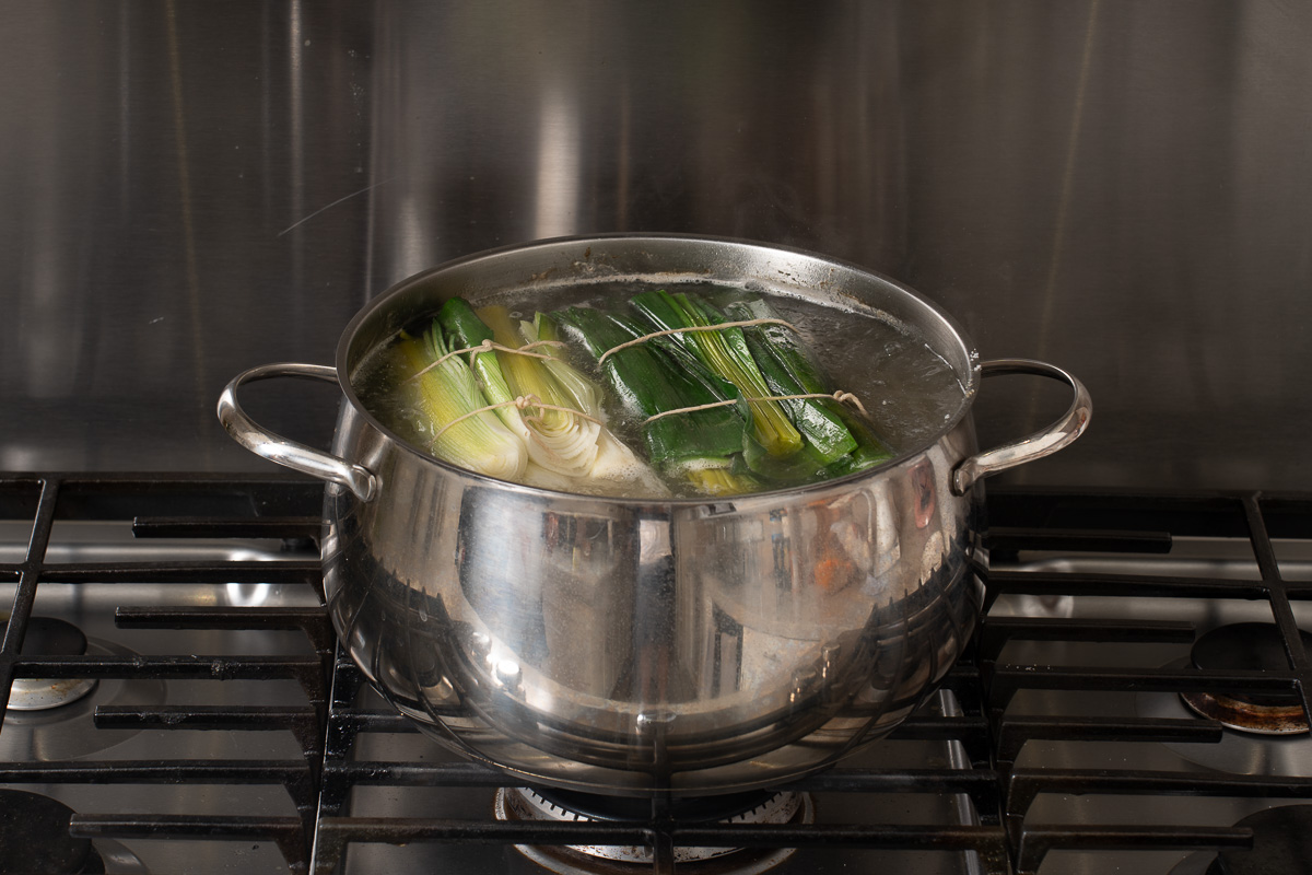 Pork broth simmering in a large pot on the stove.