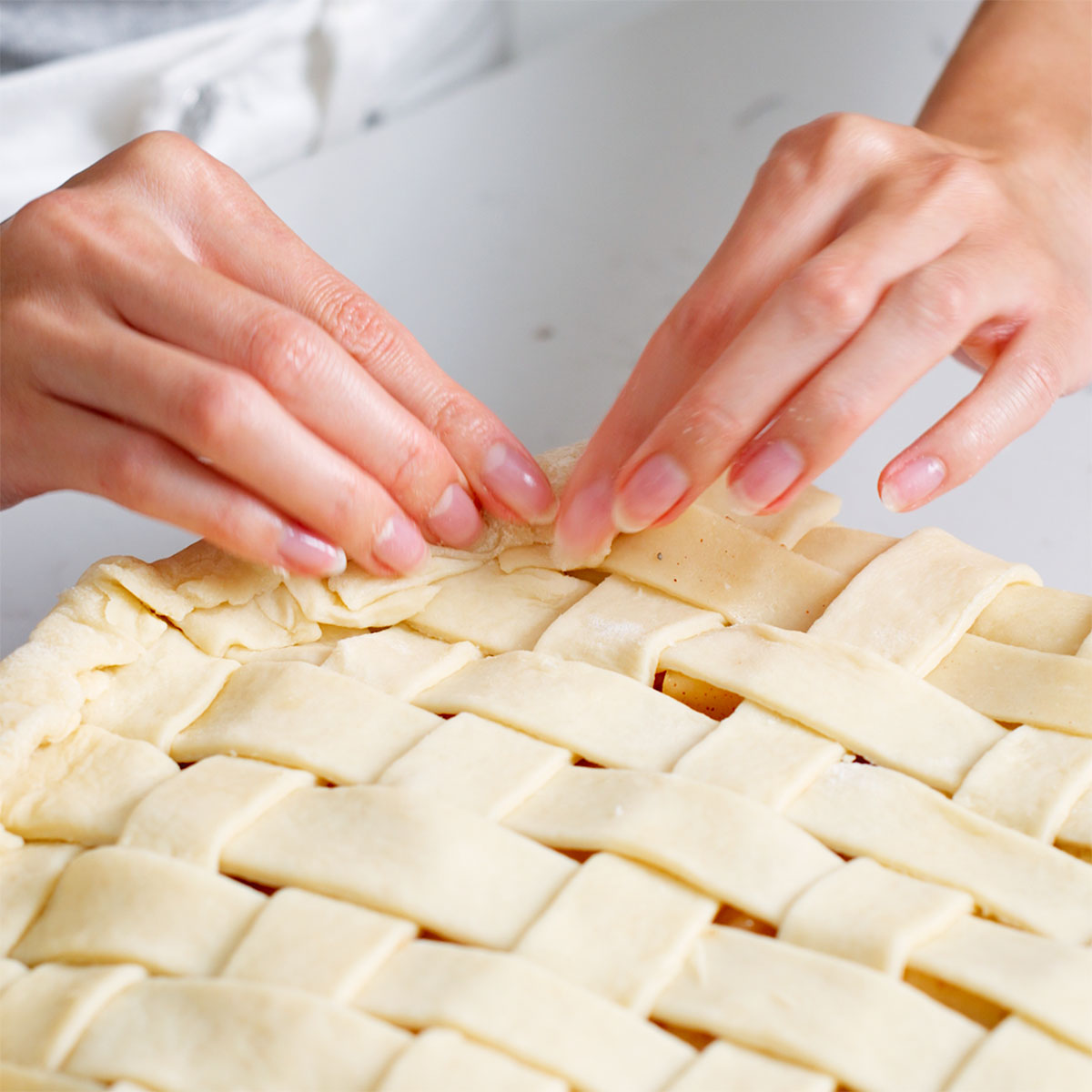 Crimping the edge of the apple pie crust.