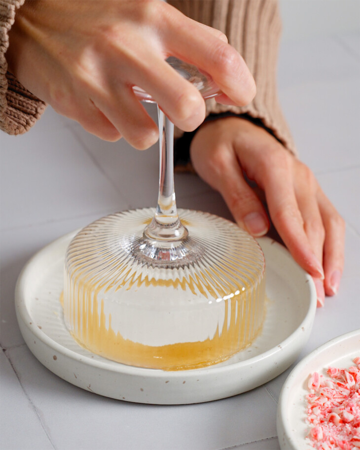 Pressing a coup glass rim into a plate of honey.
