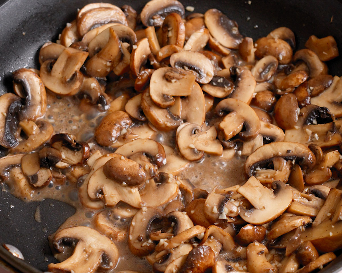 Mushrooms and garlic cooking in a large skillet.