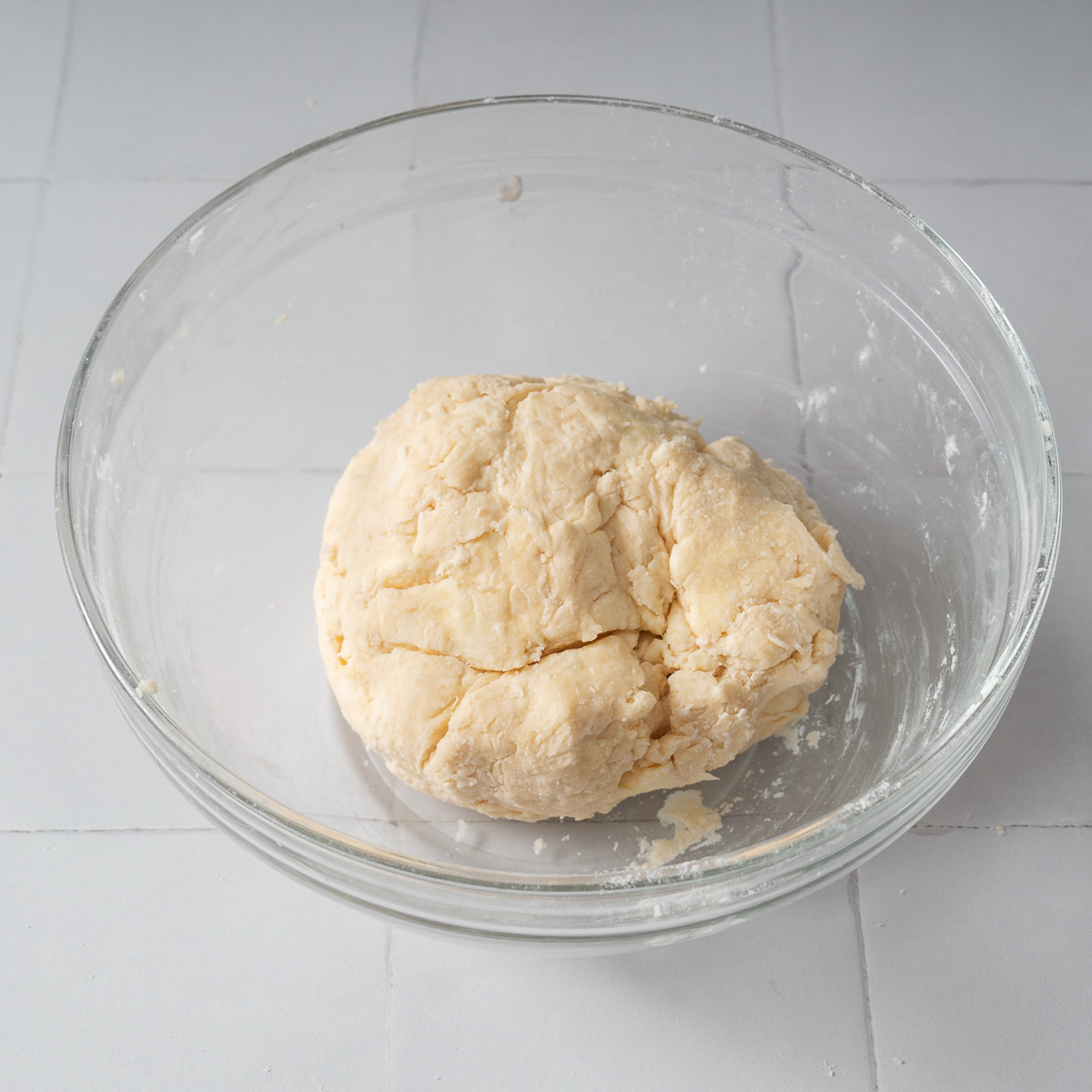 A ball of pie crust dough in a mixing bowl.