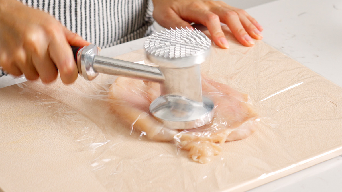 Tendering a chicken breast with a meat mallet.