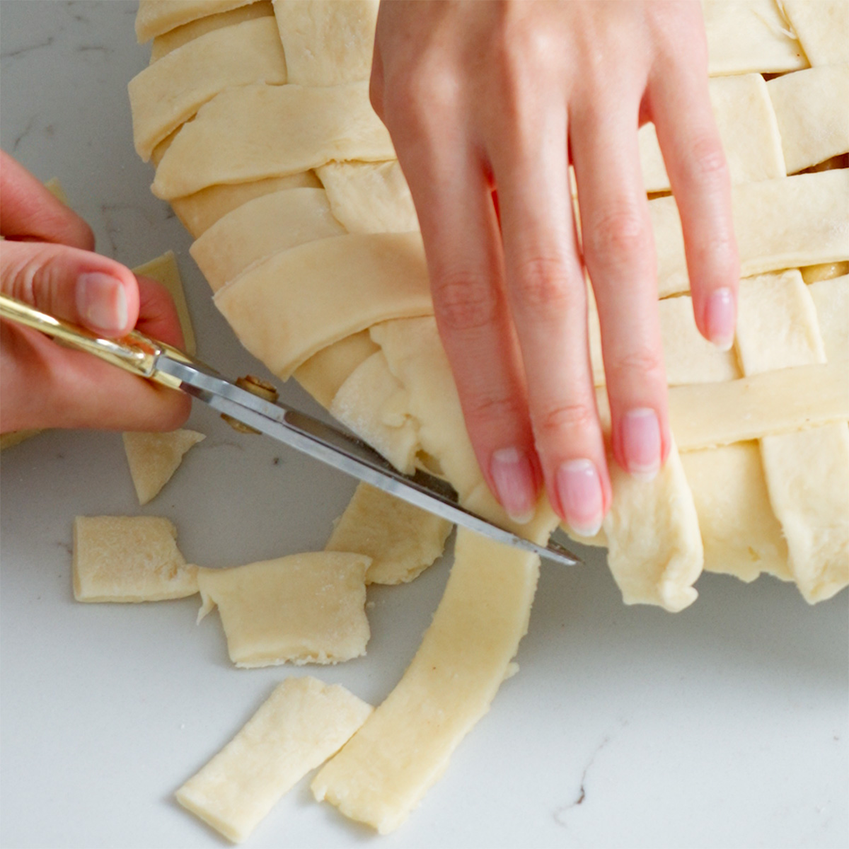 Trimming the excess edge of a lattice crust on a pie.