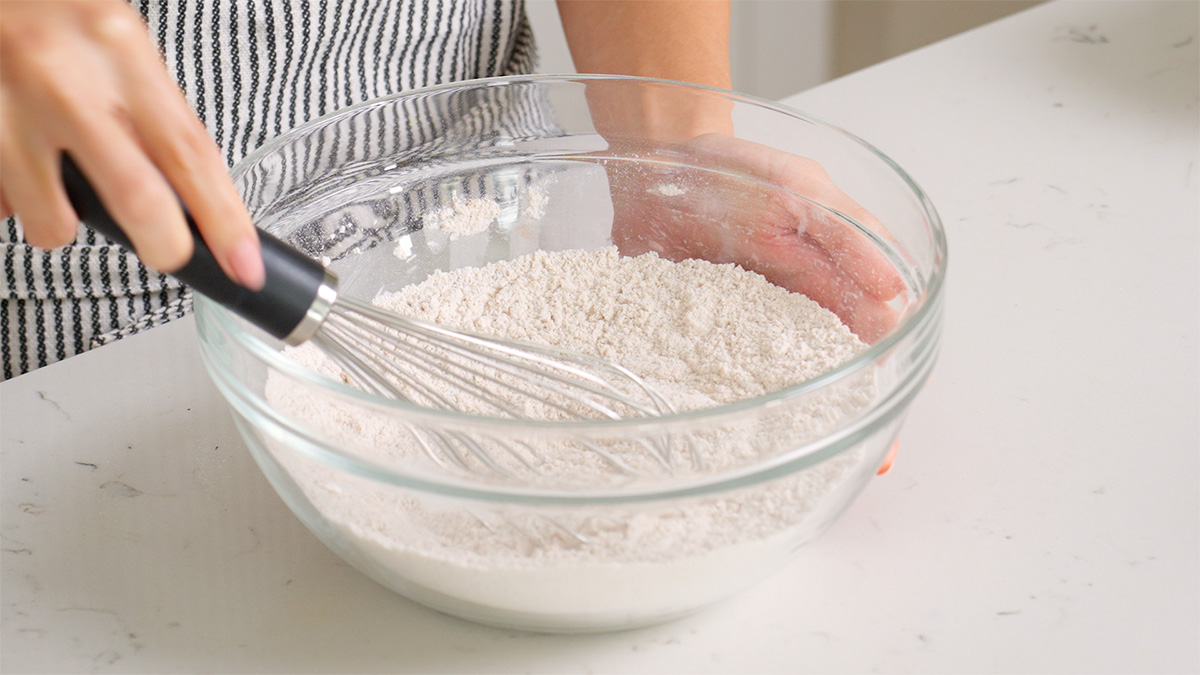 Someone whisking together the dry ingredients for pumpkin bread.