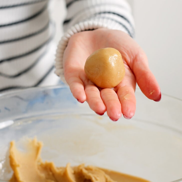 A ball of sesame cookie dough rolled in the palm of a hand.