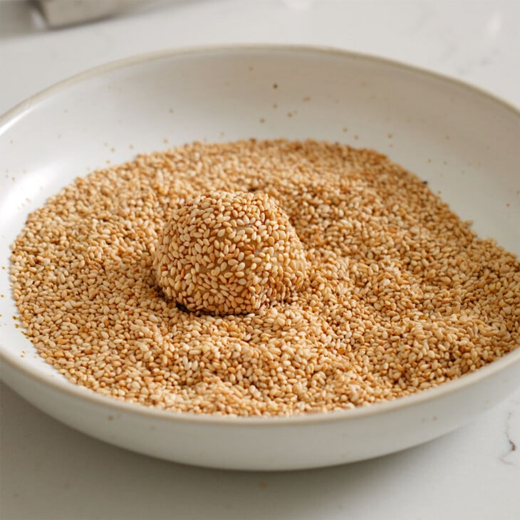 A ball of sesame cookie dough rolled in toasted sesame seeds.