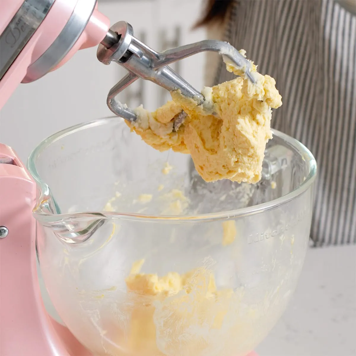 Eggs and vanilla extract mixed into butter and sugar inside a stand mixer.