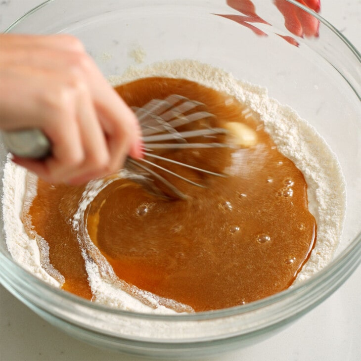 Mixing the wet ingredients into the dry ingredients for sesame cookies.
