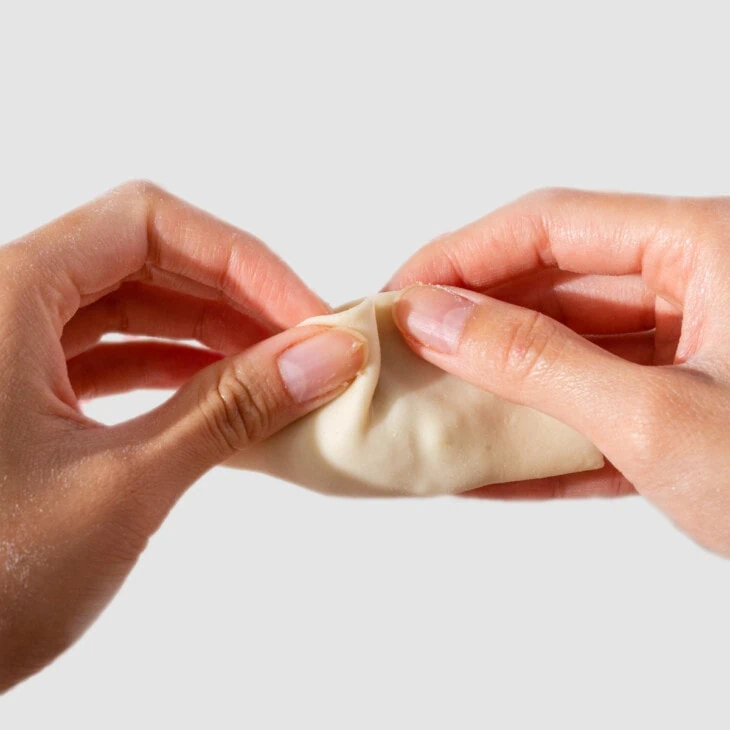 Pleating a dumpling wrapper.