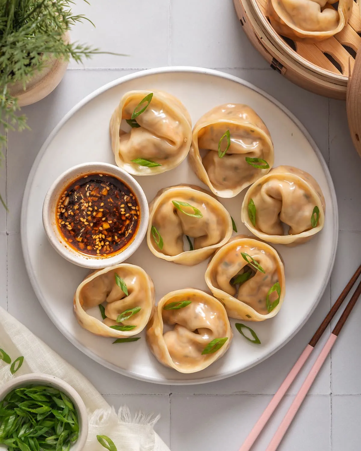 Looking down at a plate of Korean kimchi mandu surrounded by table settings.