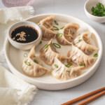 A table scene featuring a plate of steamed dumplings.
