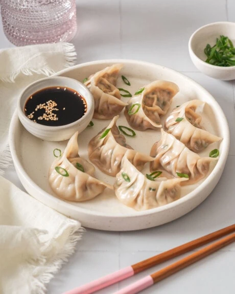 A table scene featuring a plate of steamed dumplings.