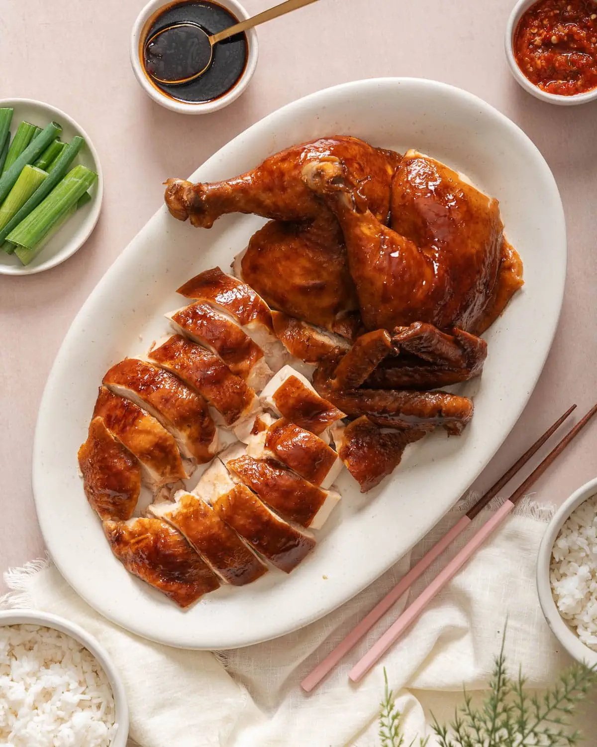 A top down view of a carved soy sauce chicken with sides near by.
