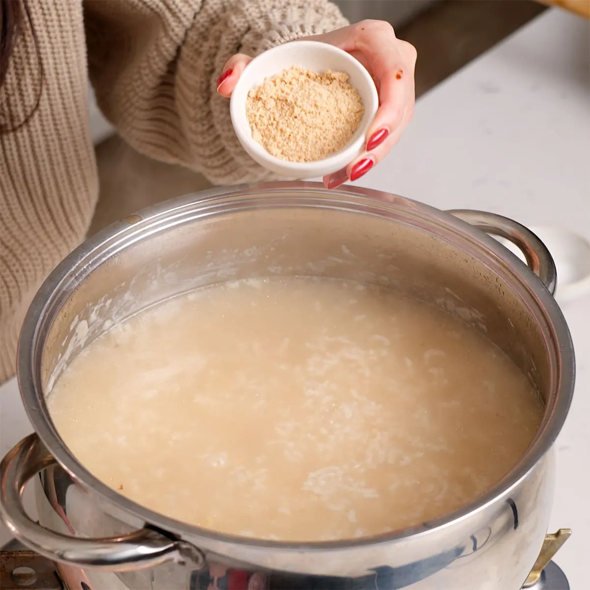 Seasoning Vietnamese chicken rice porridge to taste with chicken bouillon powder.