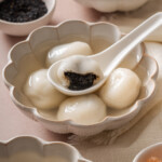 A bowl of tang yuan with a half eaten tang yuan in a spoon.