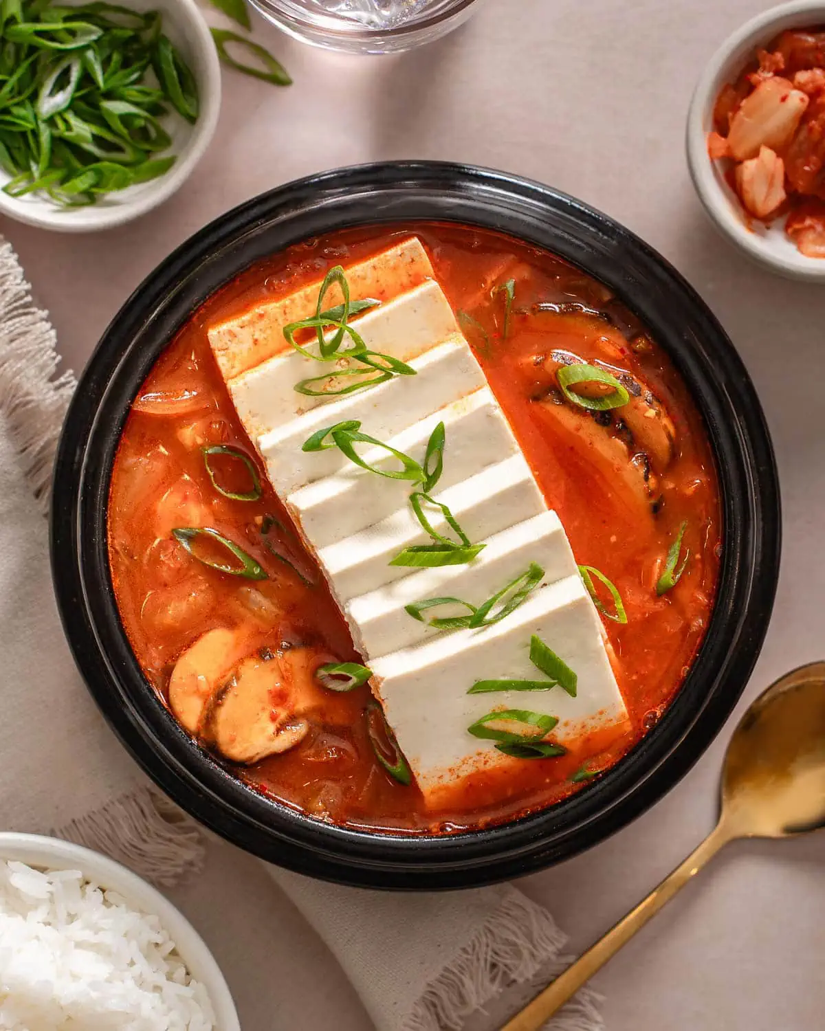 A top down view of a small stone pot of kimchi jjigae.