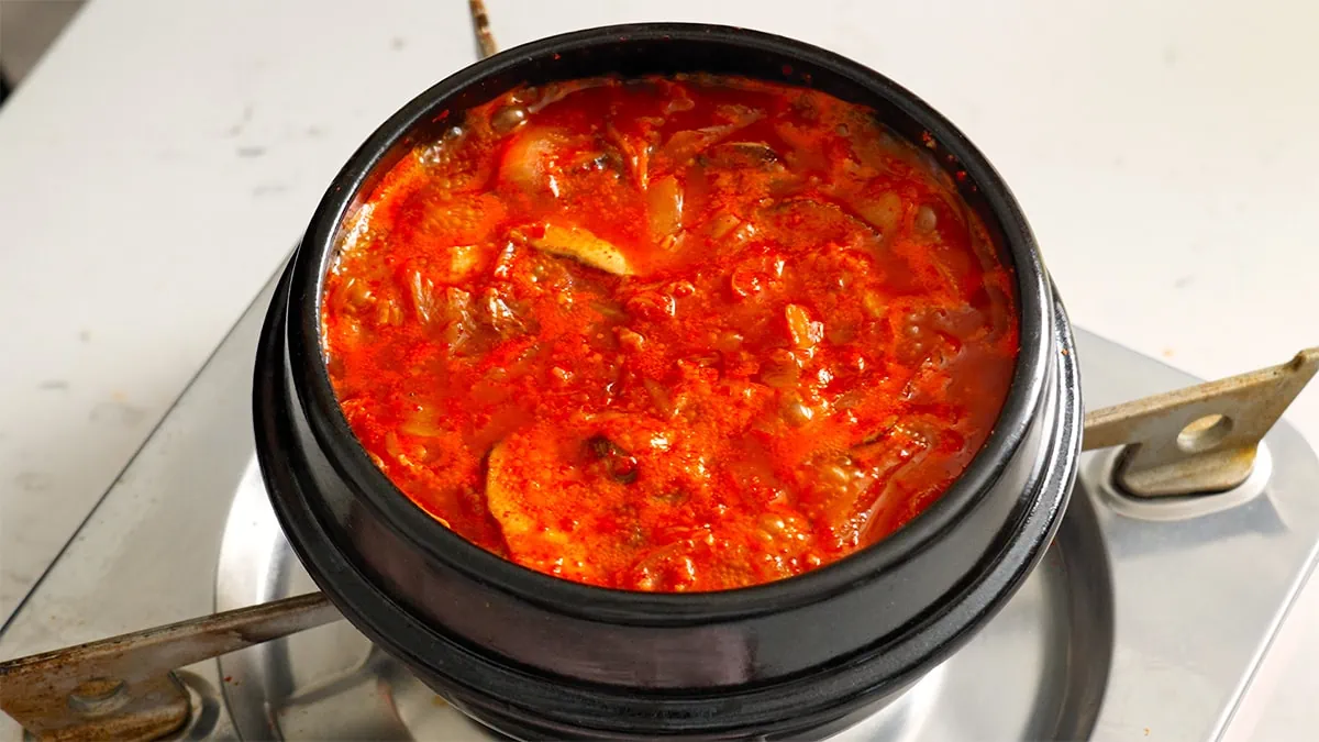 Kimchi jjigae boiling in a stone pot.