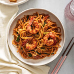 Looking down at a plate of mie goreng made with shrimp.