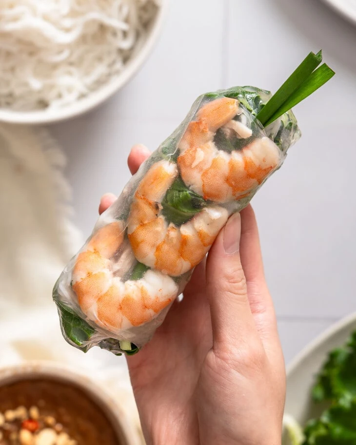 Someone holding up a goi cuon spring roll.
