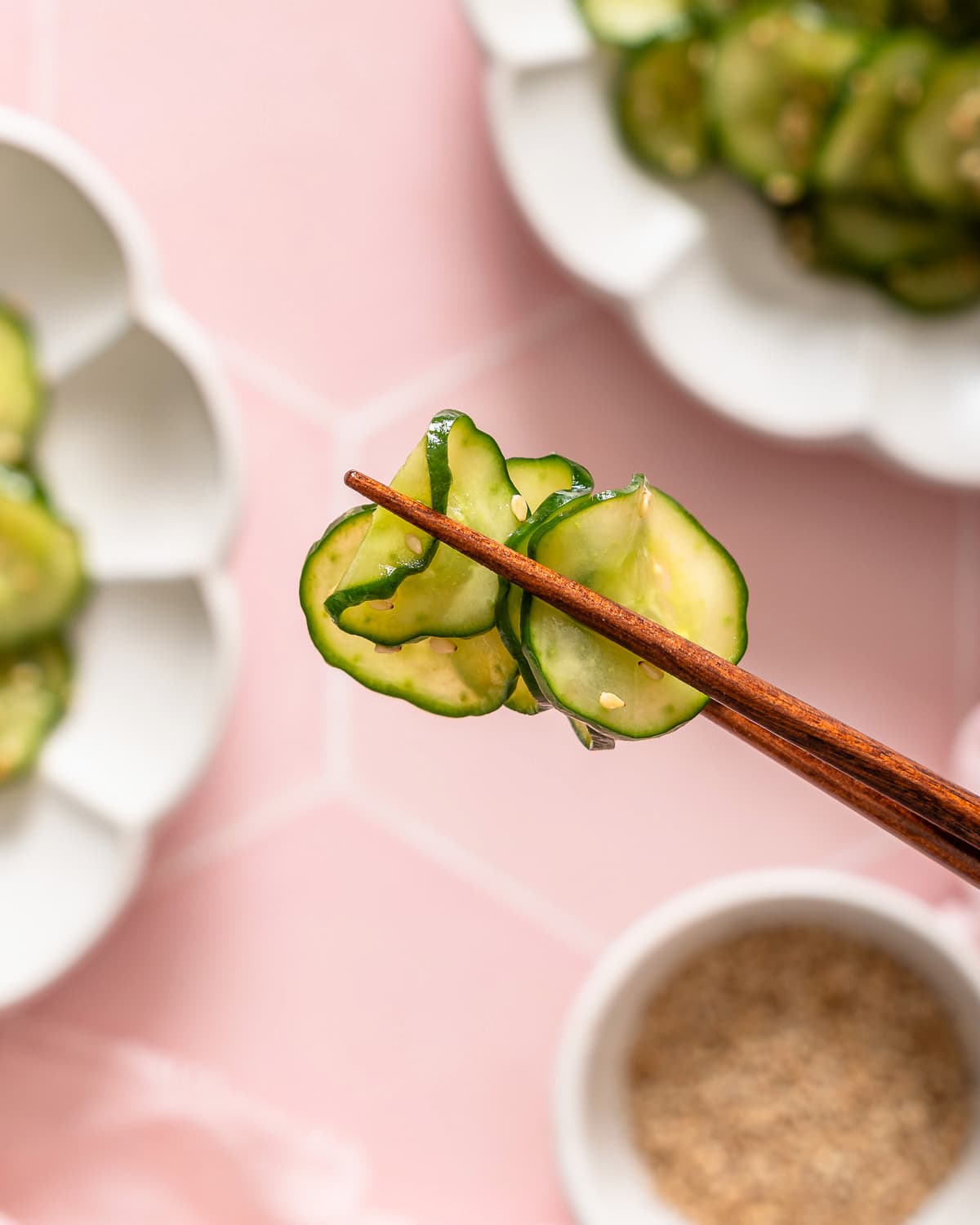 A pair of chopsticks holding up pieces of a Japanese cucumber salad.