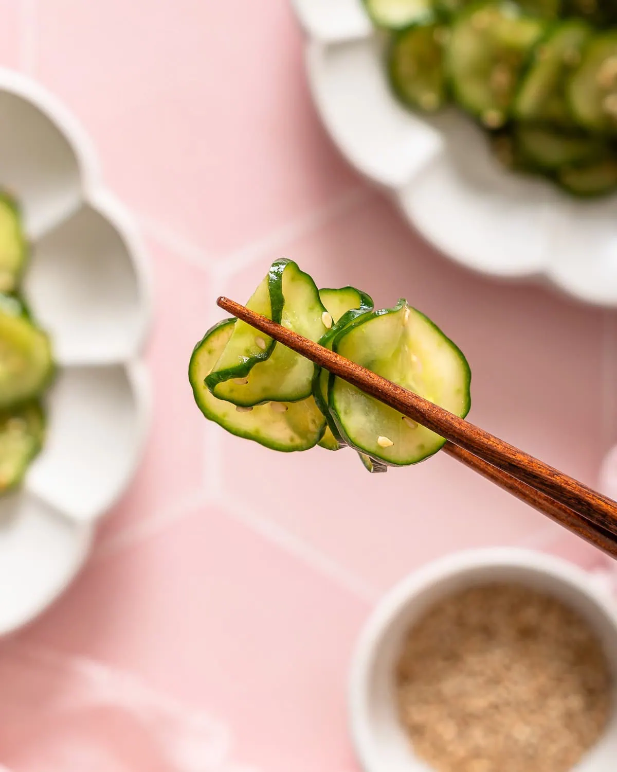 A pair of chopsticks holding up pieces of a Japanese cucumber salad.