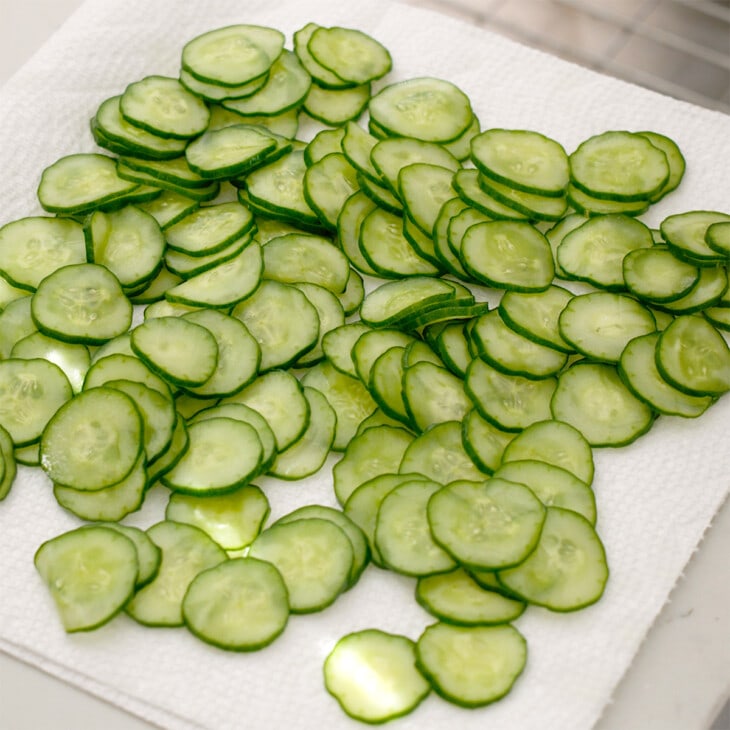 Sliced japanese cucumbers drying on a sheet of paper towels.