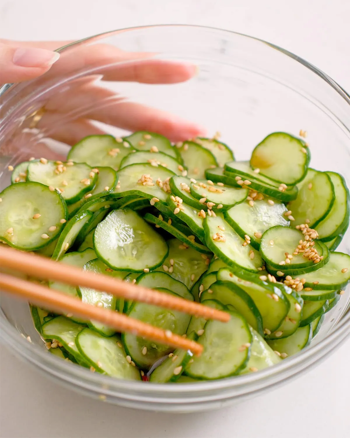 Mixing together sunomomo salad in a glass bowl.