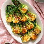 Looking down at a platter of garlic bok choy on a tiled surface.