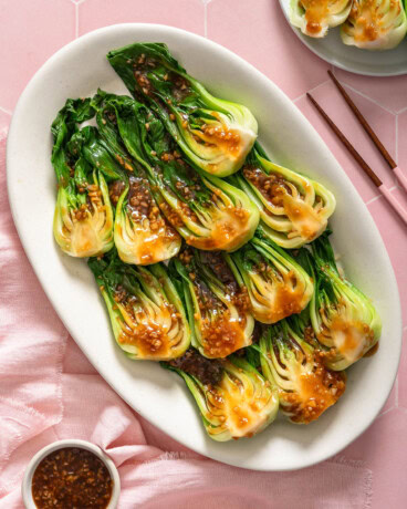 Looking down at a platter of garlic bok choy on a tiled surface.