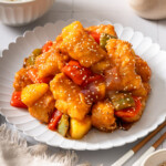 A plate of sweet and sour fish garnished with sesame seeds.