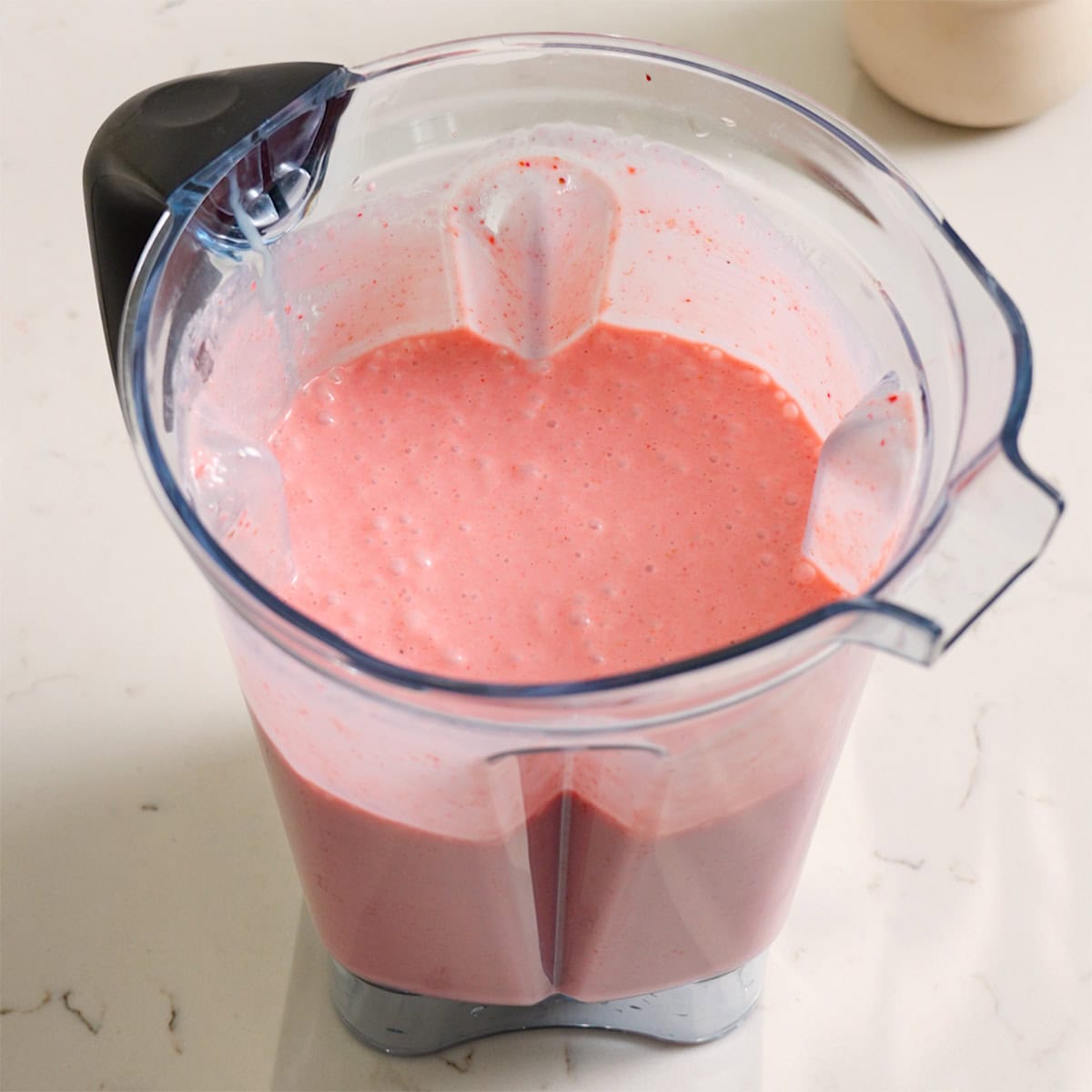 Strawberry puree blended inside of a large blender.