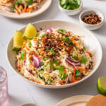 A large serving dish with vietnamese chicken salad on a tiled surface.