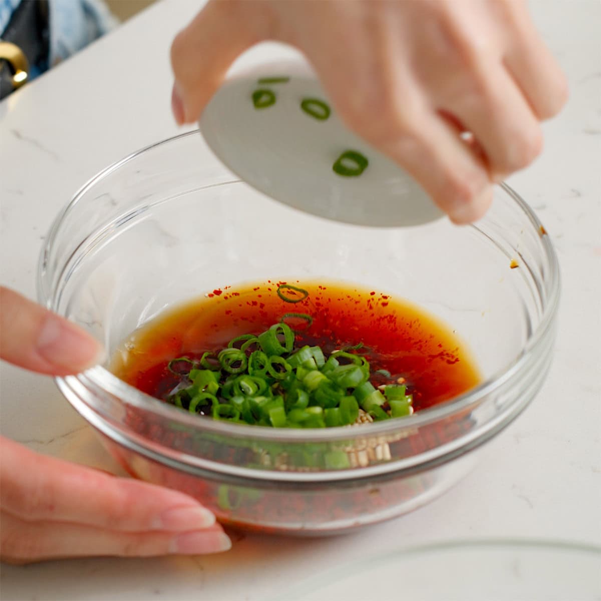 Mixing together the dipping sauce for Korean seafood pancakes in a glass bowl.