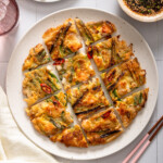 A top down view of a korean seafood pancake sliced into pieces.
