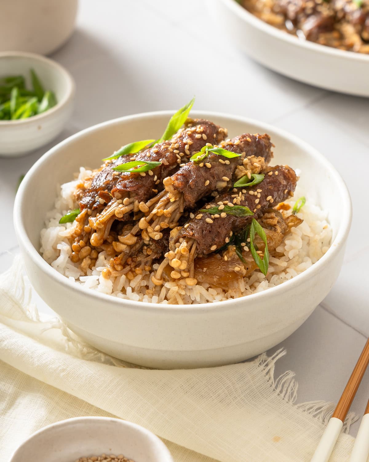 A small bowl of rice topped with beef enoki rolls.